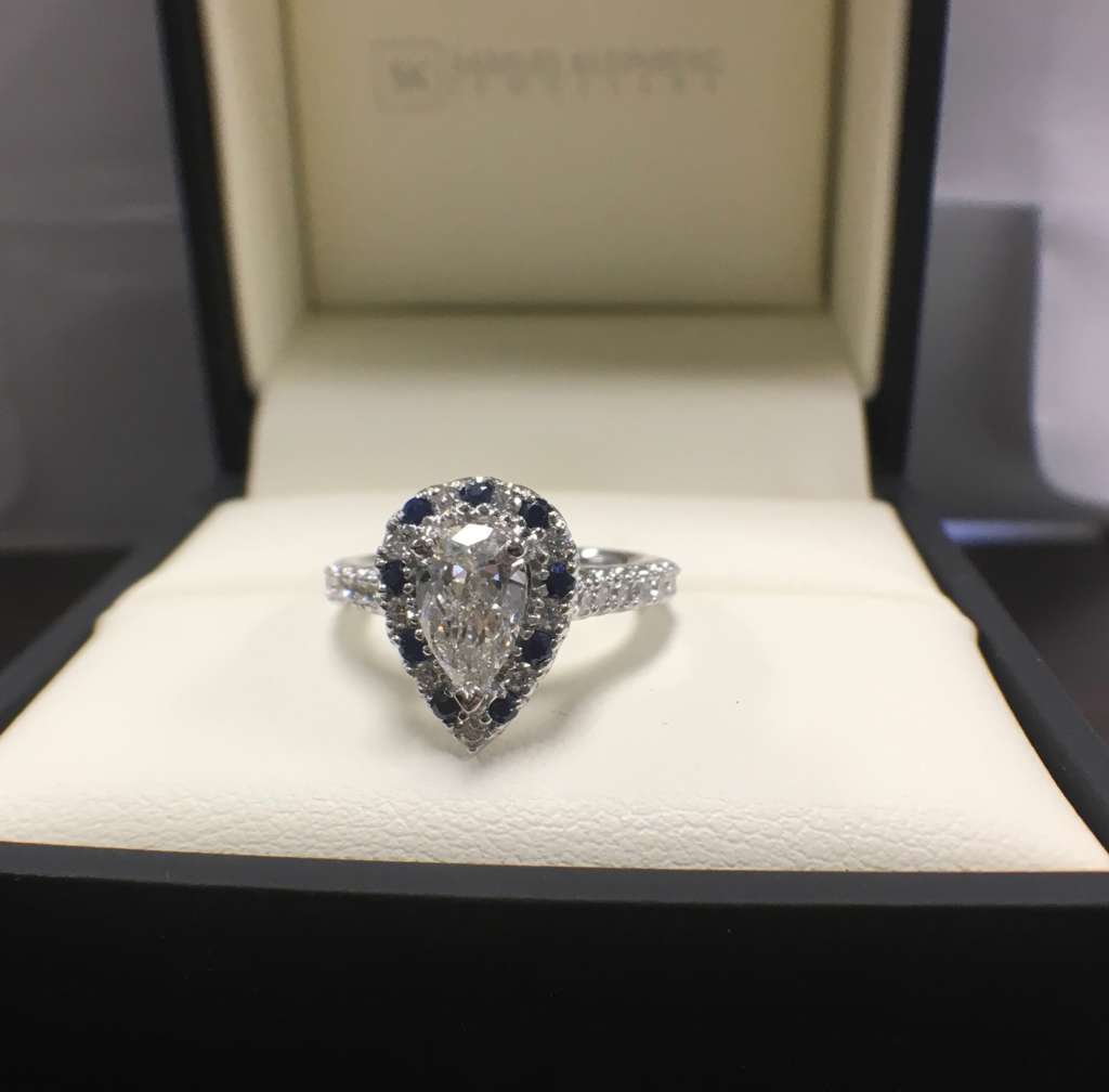 Pear shape diamond halo engagement ring with blue sapphires